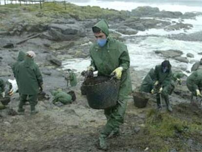 Varios voluntarios recogen restos de fuel en una zona de la costa de la localidad coruñesa de Muxía.