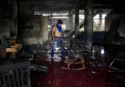 Um homem limpa os escombros de uma casa incendiada onde seis pessoas morreram durante os protestos na em oposição ao governo de Daniel Ortega, em Manágua (Nicarágua), no dia 16 de junho de 2018.