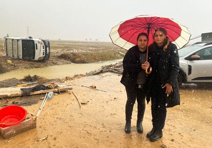 Petruta (derecha) y Alice Sandu posan delante de la furgoneta volcada a la que se encaramaron sus padres en la Albufera (Valencia), el 29 de octubre.