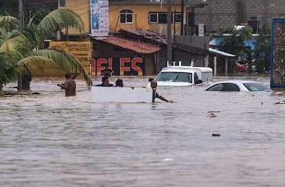 Personas caminan por una calle inundada tras el paso del huracán 'John', este jueves en Acapulco.