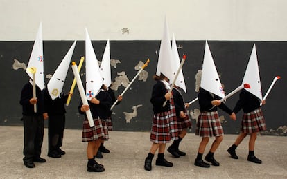 Unos niños, vestidos de penitentes, representan una procesión en un colegio de Sevilla, poco antes del inicio de las vacaciones de Semana Santa, en 2023.