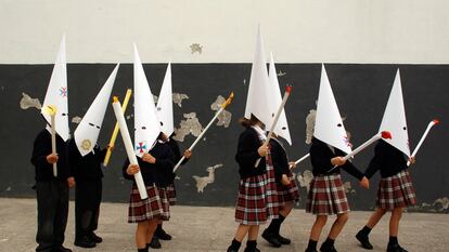 Unos niños, vestidos de penitentes, representan una procesión en un colegio de Sevilla, poco antes del inicio de las vacaciones de Semana Santa, en 2023.