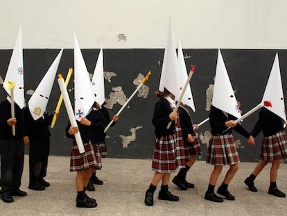 Unos niños, vestidos de penitentes, representan una procesión en un colegio de Sevilla, poco antes del inicio de las vacaciones de Semana Santa, en 2023.