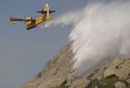 Un hidroavión expulsa agua para sofocar el incendio declarado en el término municipal de Bustarviejo.