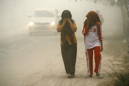 Dos personas caminan por una vía cubierta de ceniza volcánica tras la erupción del monte Kelud en Solo, Java Central (Indonesia), 14 de febrero de 2014.