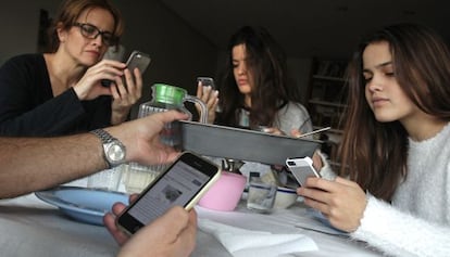 Una familia almuerza mientras chatean y navegan con sus moviles 