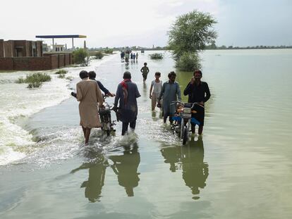 Un grupo de residentes lleva sus pertenencias en la provincia de Punjab durante las inundaciones de Pakistán del verano pasado.