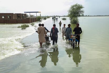 Un grupo de residentes lleva sus pertenencias mientras caminan por un área inundada en la provincia de Punjab, el miércoles.