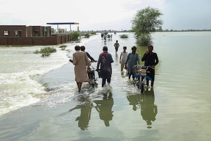 Un grupo de residentes lleva sus pertenencias mientras caminan por un área inundada en la provincia de Punjab, el miércoles.