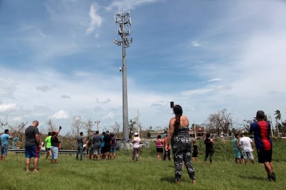 Un grupo de personas se detiene junto a una antena de telefonía para tratar de coseguir cobertura móvil, en Dorado (Puerto Rico).
