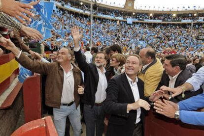 Esteban González Pons, Mariano Rajoy y Alberto Fabra responden a los saludos en la plaza de toros de Valencia, con unos 15.000 asistentes al mitin.