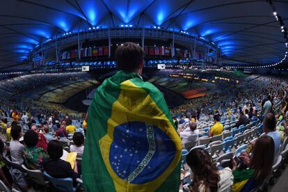 Un espectador cubierto con una bandera brasileña echa un vistazo al estadio de Maracaná a la espera de que comience el espectáculo.