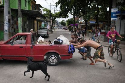 Um grupo de vizinhos ajuda a empurrar um carro no bairro.