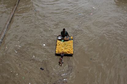 Lluvias torrenciales causaron inundaciones y daños en la capital financiera de Pakistán, Karachi. En la imagen, un vendedor de frutas navega por una carretera inundada, este lunes.