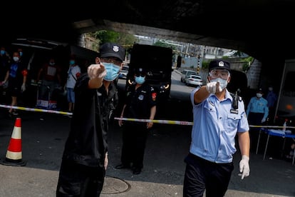 Agentes de las fuerzas de seguridad china se dirigen a los fotógrafos junto al mercado de Xinfadi, en Pekín, el pasado 20 de junio.