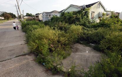 Un hombre y un niño pasean cerca de una casa abandonada tras el paso del Katrina. Otras casas colindantes han sido reparadas.