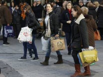 Varias mujeres pasean por la calle Preciados de Madrid tras realizar algunas compras en los establecimientos de la zona, con motivo de las fiestas navideñas.