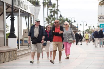 Varios turistas extranjeros pasean por el paseo maritimo de La Cahiruela en Torremolinos (Málaga).