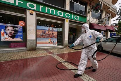 Un operario desinfecta la entrada de una farmacia en una calle de Ávila durante la presentación de los trabajos de refuerzo en limpieza que se van a realizar en la ciudad para evitar contagios por covid-19.