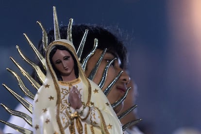 Una mujer carga una efigie de la Virgen de Guadalupe.