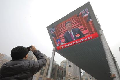 Un hombre fotografía una pantalla que muestra un discurso de Xi Jinping en Pekín.