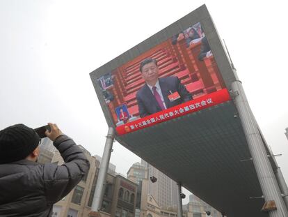 Un hombre fotografía una pantalla que muestra un discurso de Xi Jinping en Pekín.
