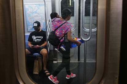 A young woman sells candy with her son in tow inside on the New York subway. 