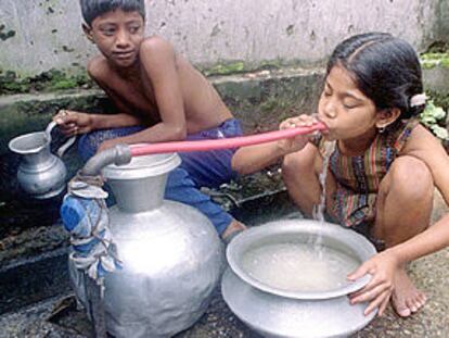 Una niña bebe con una goma de un caño público en Daca, capital de Bangladesh, en 1996.