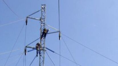 Los operarios de una compa&ntilde;&iacute;a el&eacute;ctrica reparan una torre de alta tensi&oacute;n.