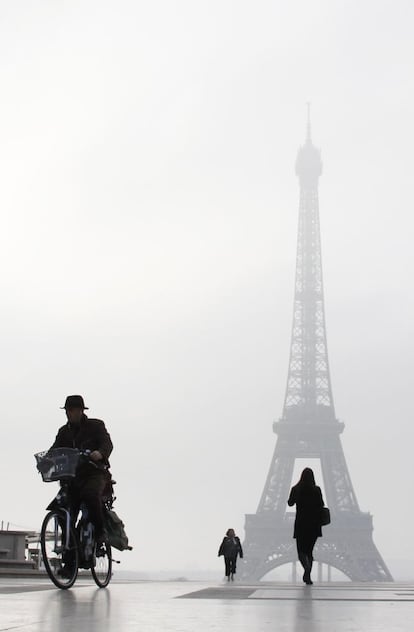 Un hombre monta en bicicleta en la plaza de Trocadero en París con la torre Eiffel al fondo.