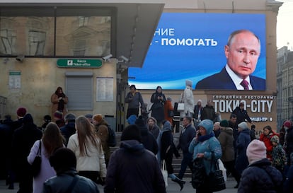 People walk past a huge digital billboard showing Russian President and presidential candidate Vladimir Putin, in St. Petersburg, Russia, 14 March 2024