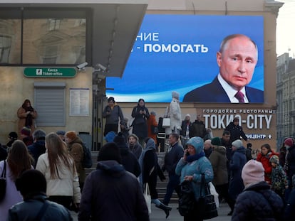 People walk past a huge digital billboard showing Russian President and presidential candidate Vladimir Putin, in St. Petersburg, Russia, 14 March 2024