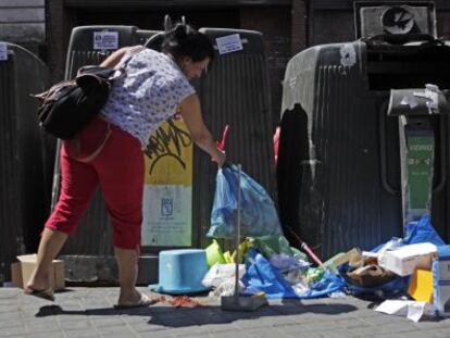 Una mujer deja una bolsa de basura en el suelo en Madrid.