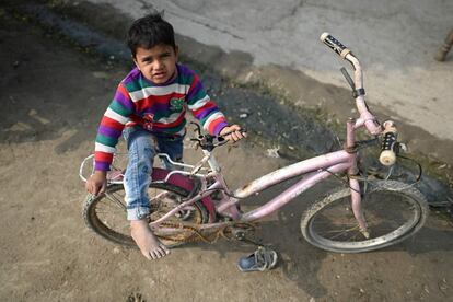 Un niño, junto a una bicicleta en un asentamiento temporal a lo largo del río Yamuna en Nueva Delhi (India). Las autoridades ordenaron el cierre de restaurantes y oficinas, en una nueva serie de restricciones para frenar las infecciones en la capital, mientras la India registró 168.063 casos en pleno avance de la tercera ola.