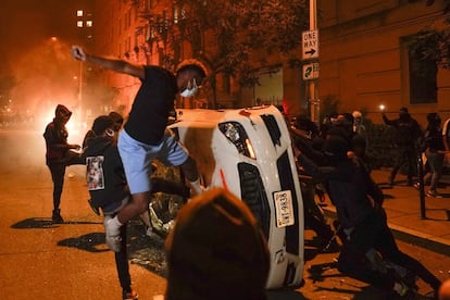 Un grupo de manifestantes destrozan algunos vehículos aparcados en las inmediaciones de la Casa Blanca en Washington, esta madrugada. Miles de manifestantes lograron llegar este domingo por la noche a las afueras de la residencia del presidente, pese al esfuerzo policial por bloquear las calles de acceso después de una tensa jornada anterior.