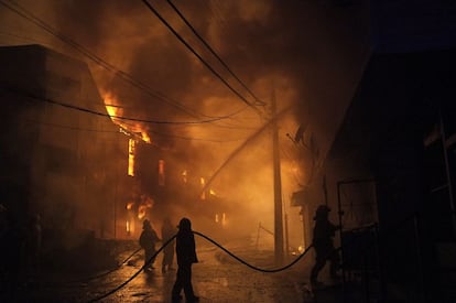 Bombeiros tentam controlar um incêndio em uma das colinas da cidade de Valparaíso.