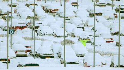 Un trabajador del aeropuerto de Edimburgo, Escocia, hace señales a un compañero en medio del aparcamiento del aeródromo, totalmente nevado.