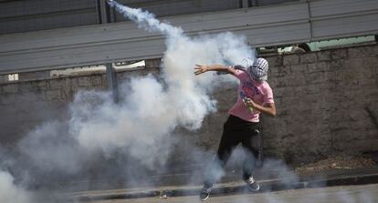 Un palestino arroja una granada de gas lanzada por soldados israelíes.