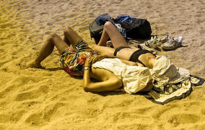 A couple sunbathes on a beach in Barcelona, Spain