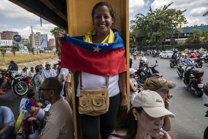 Una mujer posa para una fotografía con la bandera de Venezuela.