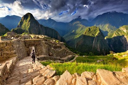 Una turista desciende unas escalinatas de piedra en la ciudadela de Machu Picchu.