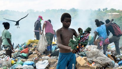 Gabriel, de 12 anos, segura a árvore de Natal que encontrou enquanto buscava comida no lixão da Piçarreira, em Pinheiro (MA).