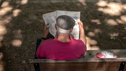 Una persona mayor leyendo el periódico en el parque Caramuel, en el barrio de Puerta del Ángel, Madrid.