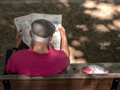 Un hombre leyendo un periódico en un parque de Madrid.