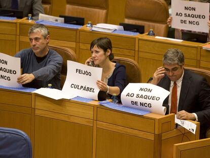 Diputados del BNG muestran carteles contra el "saqueo" de la caja, en el pleno de anteayer.