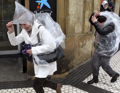  Unas mujeres se protegen con chubasqueros de una fuerte tormenta en la capital donostiarra. 