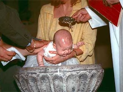 Rito del bautismo con el neófito en brazos de sus padrinos en una iglesia española.