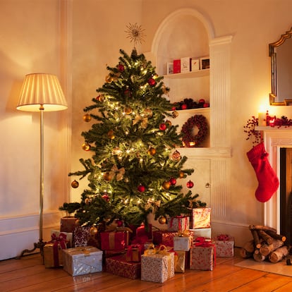Un salón con una chimenea encendida y un árbol de navidad a su lado.