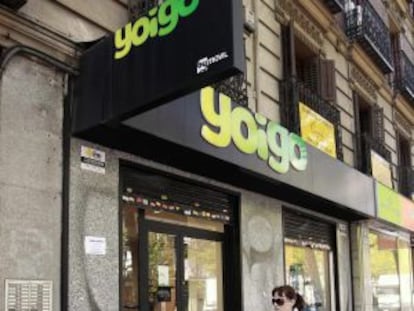 Una mujer y su hijo pasan ante una tienda de Yoigo, en Madrid.