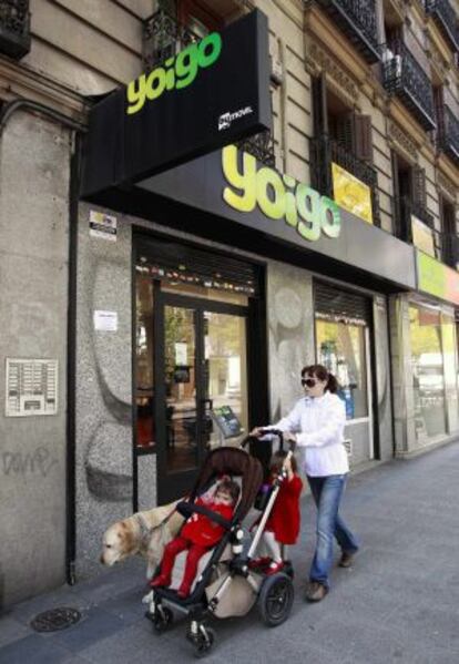 Una mujer y su hijo pasan ante una tienda de Yoigo, en Madrid.